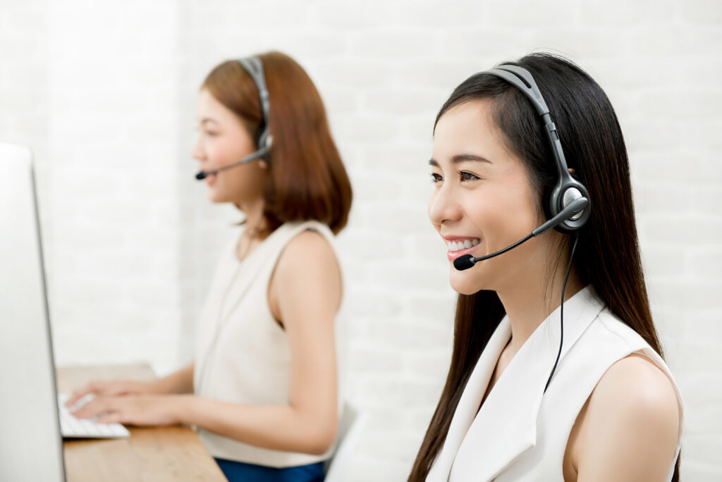 Female customer representatives with headsets assist clients